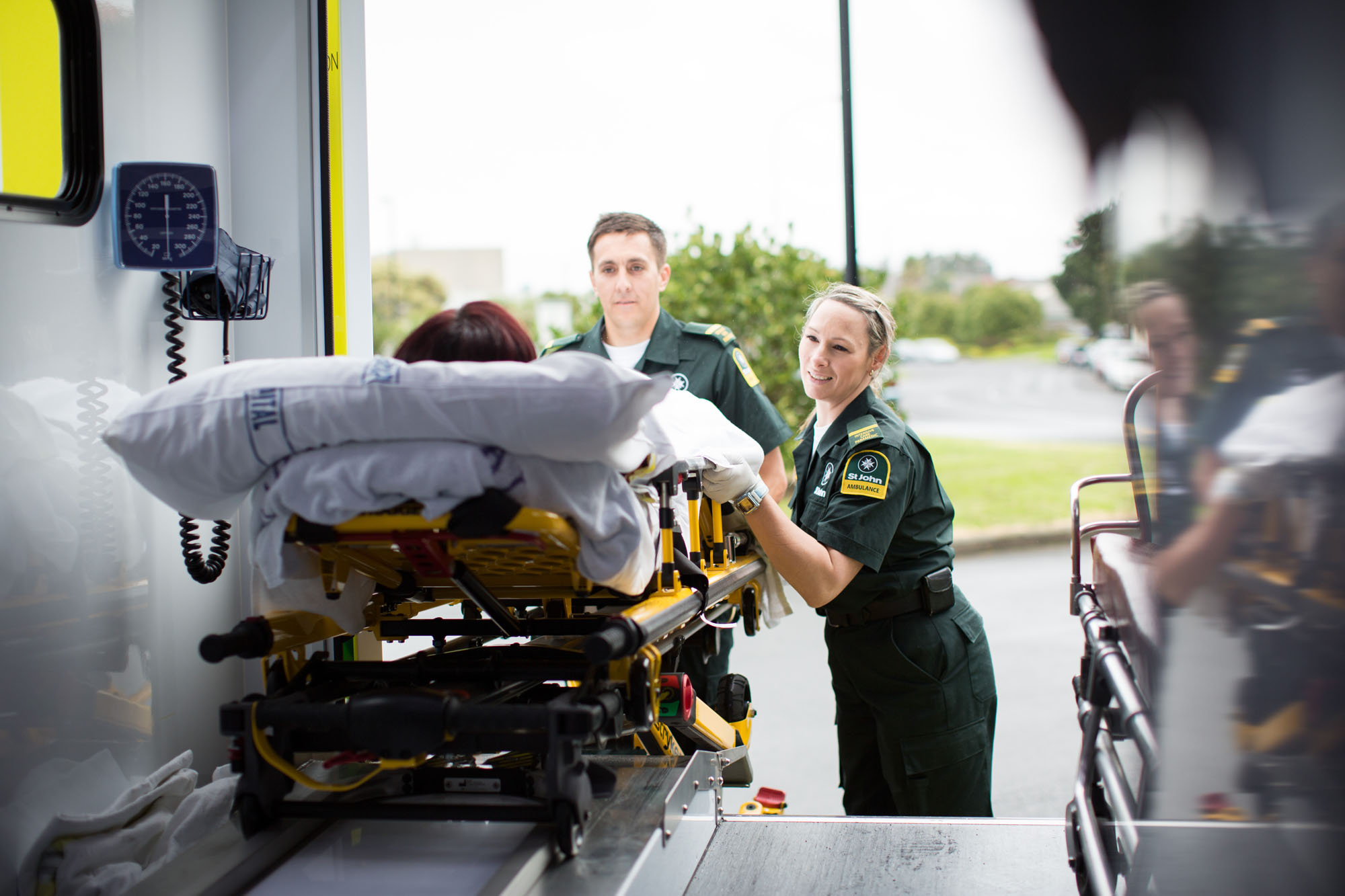 Ambulance officers pushing a stretcher into the back of an ambulance