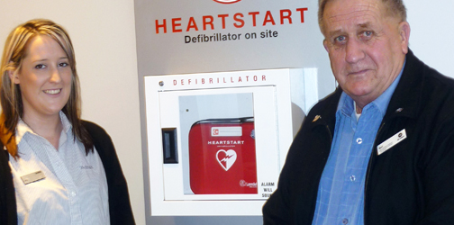 Joy next to a newly installed defibrillator