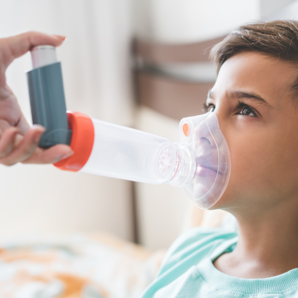 Boy using an inhaler with a spacer for asthma