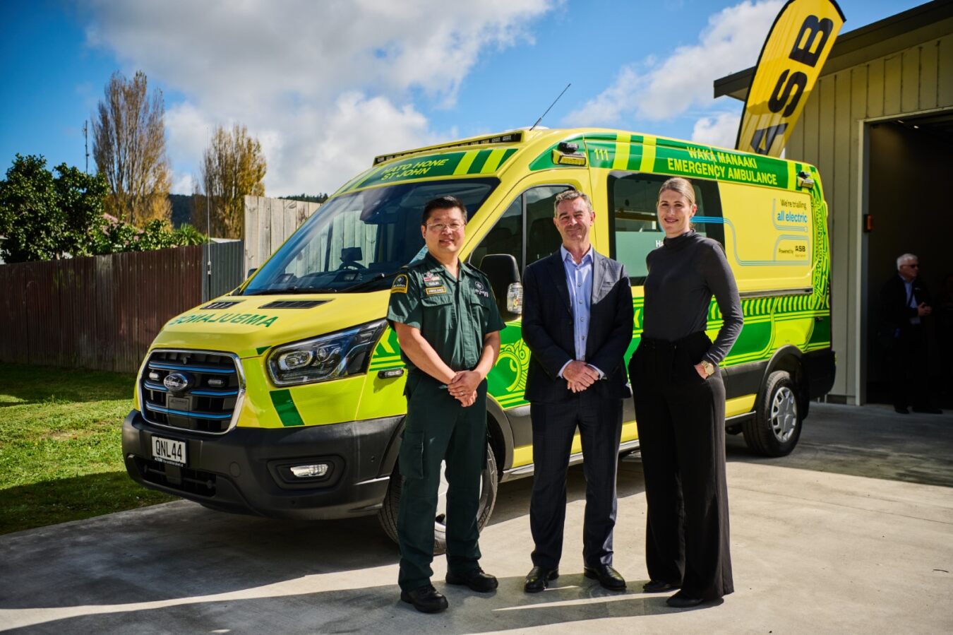 Two men and one woman stand proudly in front of Hato Hone St John's new electric emergency ambulance.