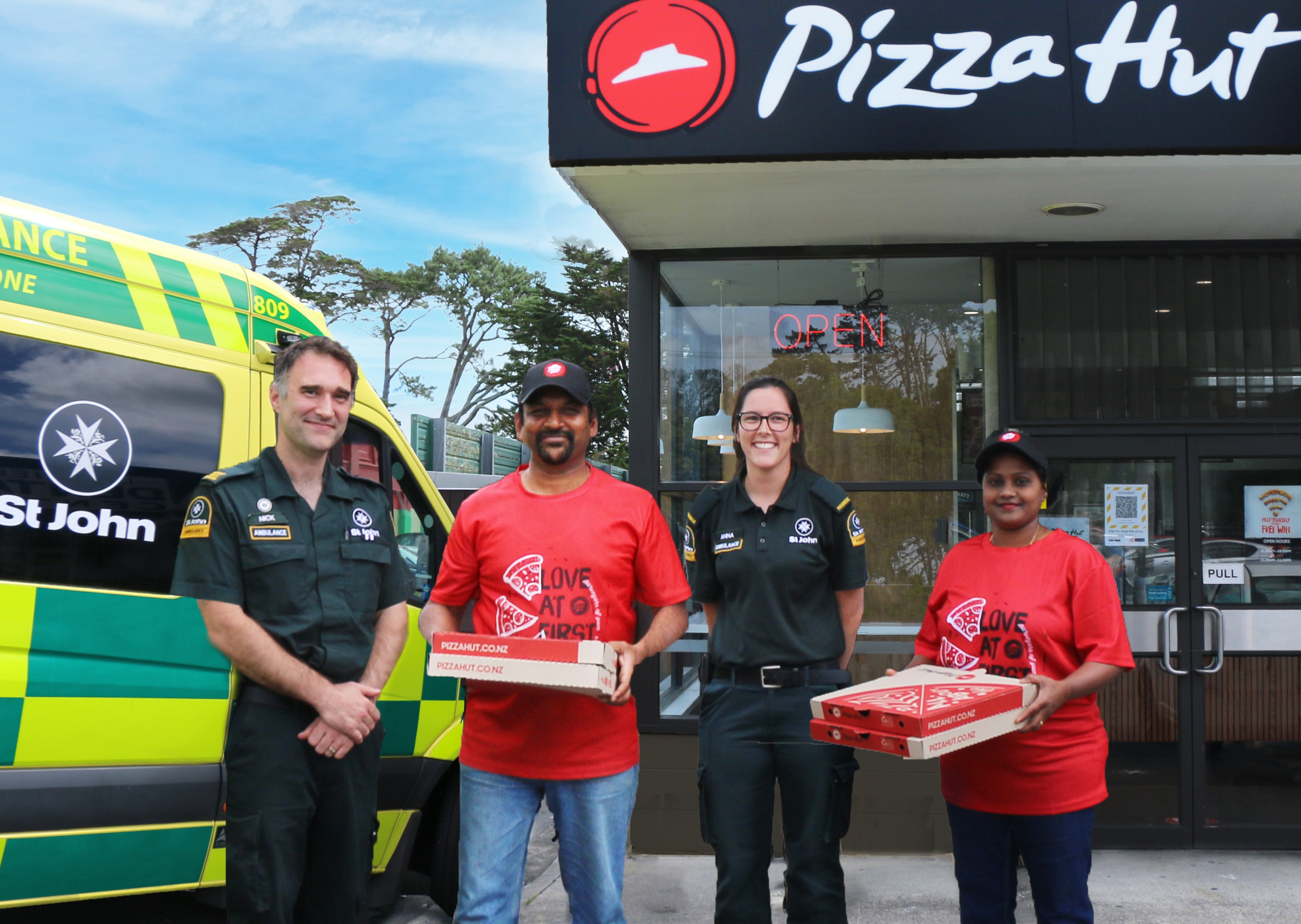 Pizza Hut and Hato Hone St John staff holding pizza boxes 