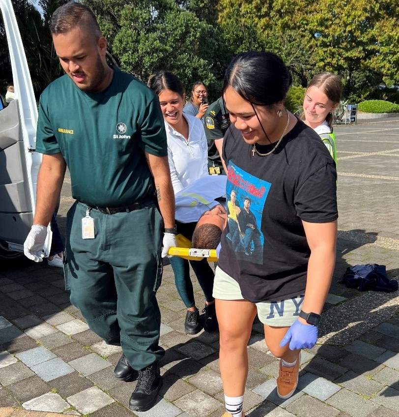 Students and ambulance officer carrying a student on a stretcher